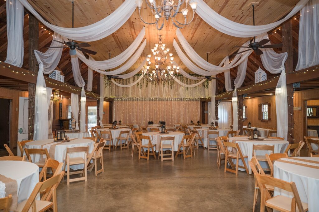 Decorated wedding venue with tables, draped fabric, and chandeliers